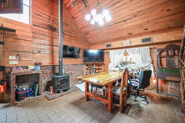 interior space with wooden walls, high vaulted ceiling, a wood stove, and a notable chandelier