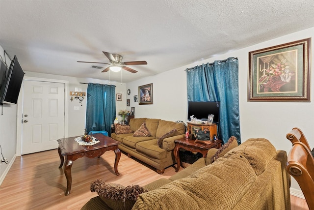 living room featuring ceiling fan, light hardwood / wood-style floors, and a textured ceiling