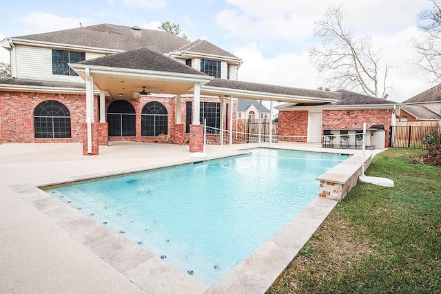 view of swimming pool with a patio, a yard, ceiling fan, and a bar