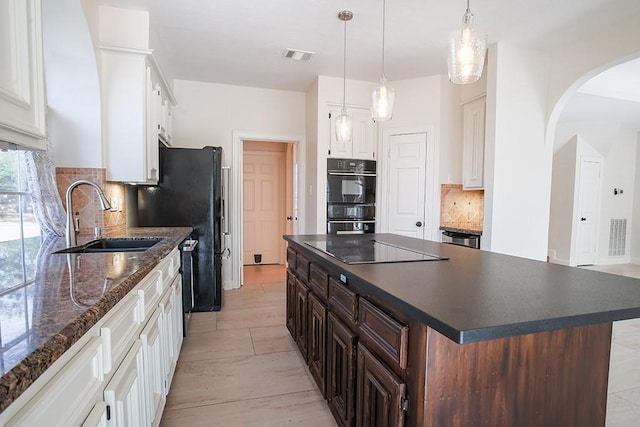 kitchen with dark brown cabinetry, sink, black appliances, a kitchen island, and white cabinets