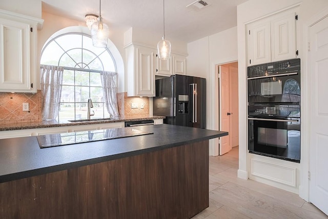 kitchen with sink, white cabinetry, tasteful backsplash, hanging light fixtures, and black appliances