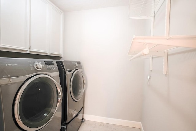 clothes washing area with washing machine and dryer and cabinets