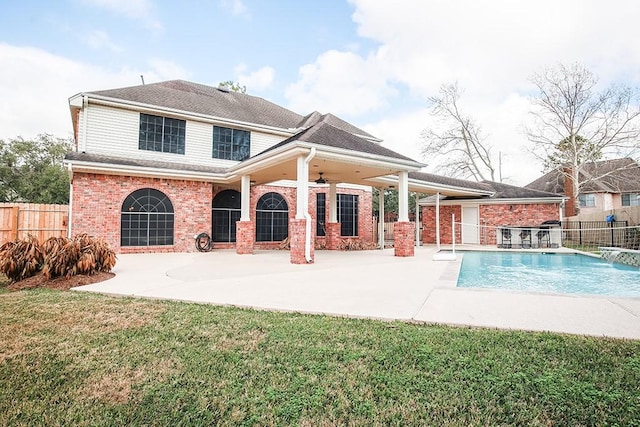 rear view of house with ceiling fan, a yard, a fenced in pool, and a patio