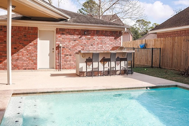 view of pool featuring exterior bar, exterior kitchen, and a patio area