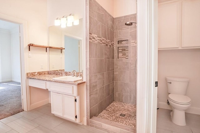 bathroom featuring vanity, toilet, and a tile shower