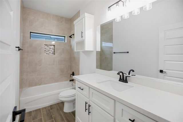 full bathroom featuring tiled shower / bath, vanity, and toilet