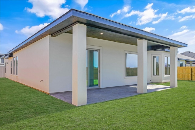 back of property with a patio area and a lawn