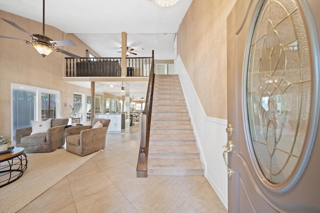 entryway with light tile patterned floors, a towering ceiling, and ceiling fan