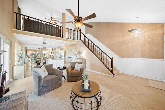 living room featuring ceiling fan with notable chandelier, vaulted ceiling, and light tile patterned floors