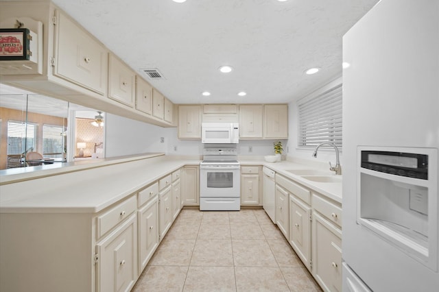 kitchen with sink, white appliances, light tile patterned floors, a textured ceiling, and kitchen peninsula