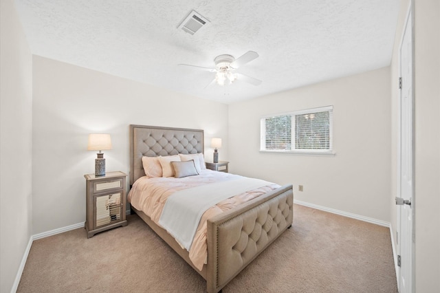 bedroom with ceiling fan, light colored carpet, and a textured ceiling