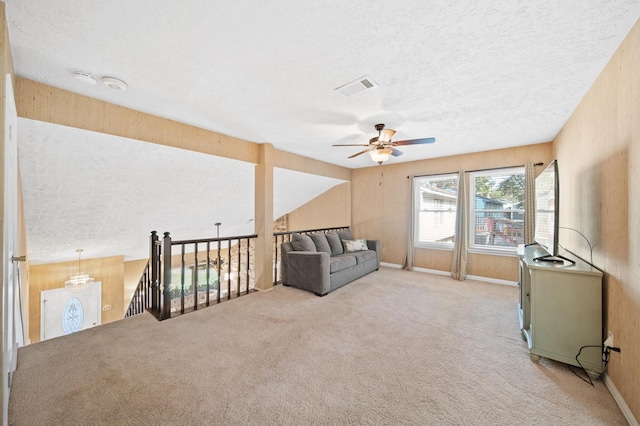 living area with ceiling fan, lofted ceiling, light carpet, and a textured ceiling