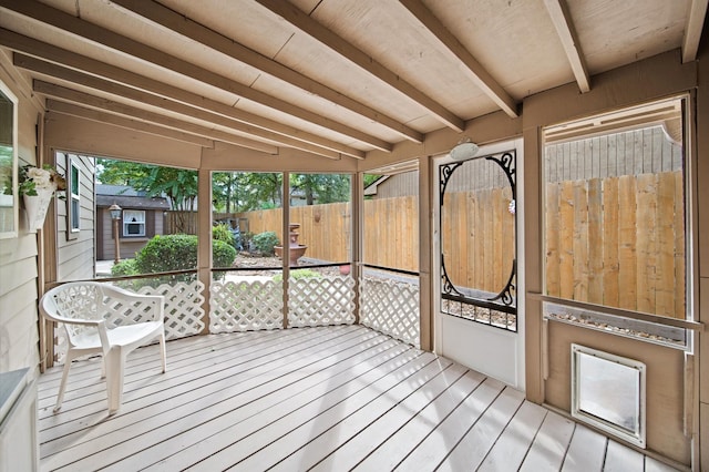 unfurnished sunroom featuring wood ceiling, plenty of natural light, and lofted ceiling with beams