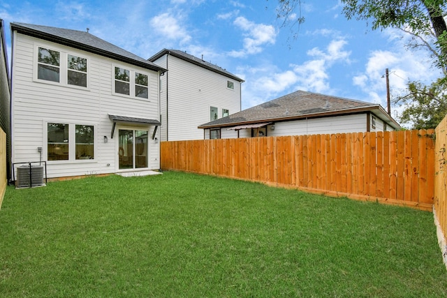 back of property with central AC and a lawn