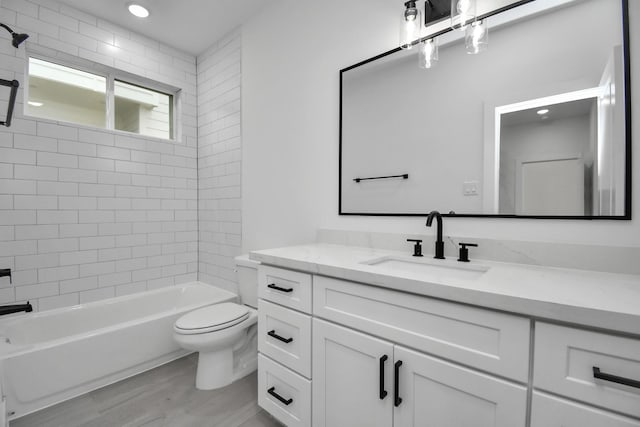 full bathroom featuring tiled shower / bath, vanity, toilet, and wood-type flooring