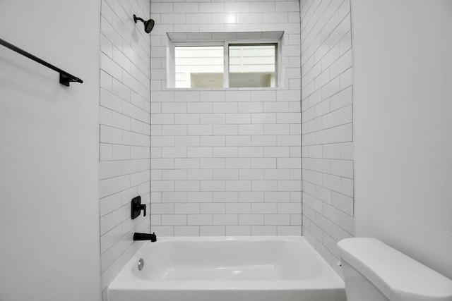 bathroom with toilet and tiled shower / bath