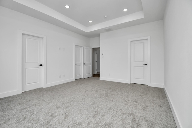 unfurnished bedroom with light carpet and a raised ceiling