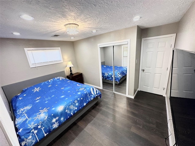 bedroom featuring a textured ceiling, wood finished floors, visible vents, baseboards, and a closet