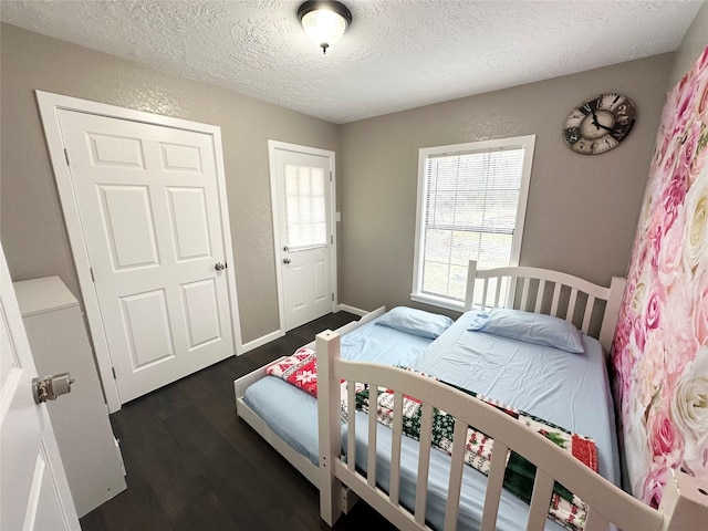 bedroom featuring dark wood-style floors, a textured ceiling, and baseboards