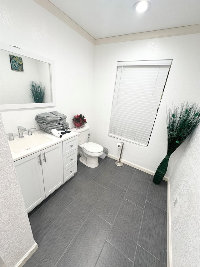 bathroom featuring toilet, baseboards, and vanity