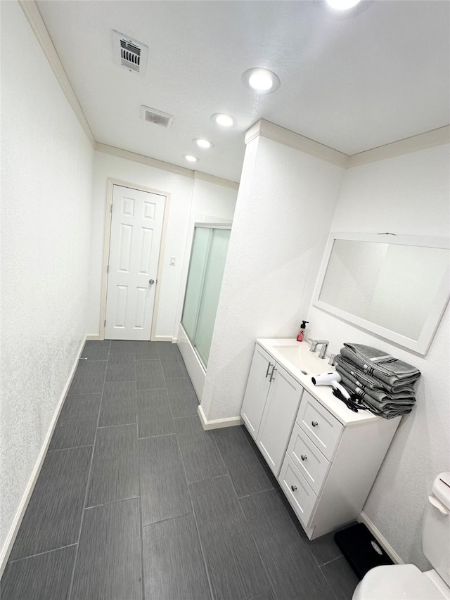 bathroom featuring walk in shower, vanity, toilet, and crown molding