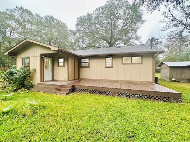 rear view of house with an outdoor structure, a lawn, and a wooden deck