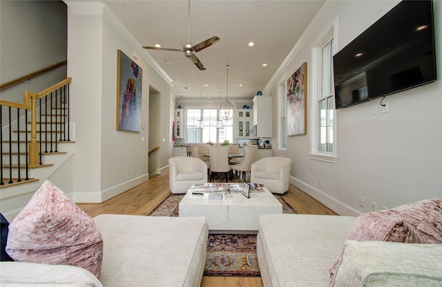 living room featuring ornamental molding, ceiling fan, and light hardwood / wood-style flooring