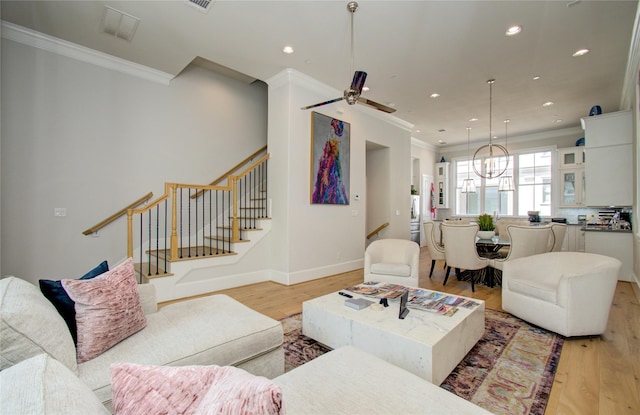 living room with crown molding, ceiling fan with notable chandelier, and light hardwood / wood-style floors