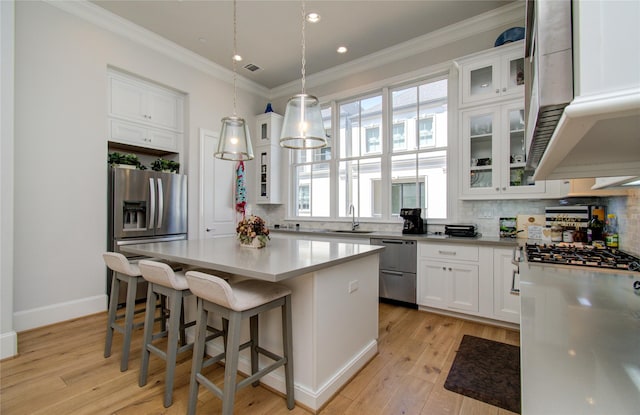 kitchen with tasteful backsplash, a center island, light wood-type flooring, stainless steel appliances, and white cabinets