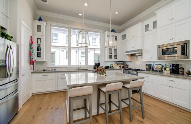 kitchen featuring white cabinetry, stainless steel appliances, a center island, and decorative backsplash