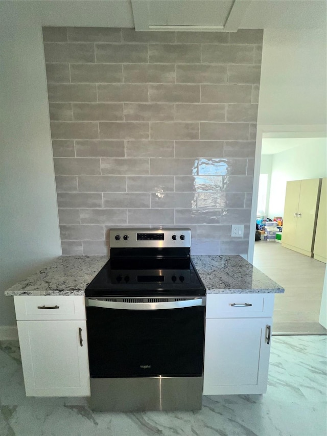 kitchen with white cabinetry, backsplash, light stone counters, and electric stove