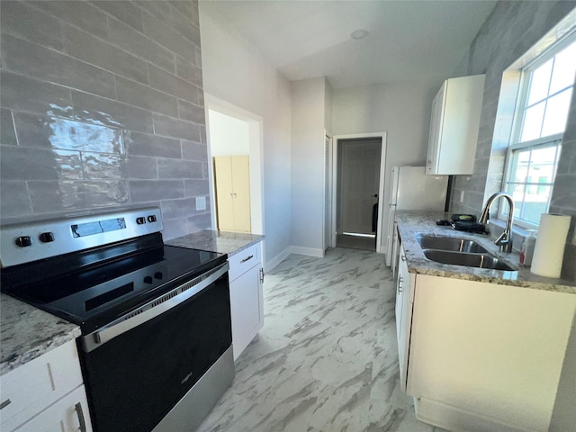 kitchen featuring white cabinetry, sink, light stone counters, and stainless steel range with electric stovetop