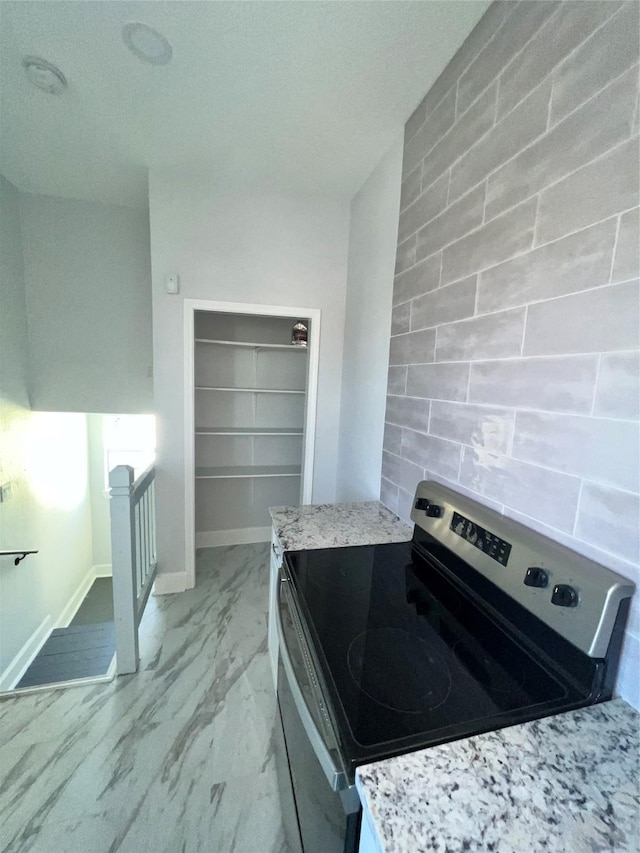 kitchen with electric stove and light stone countertops