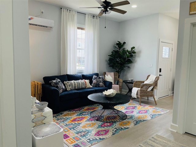 living room with an AC wall unit, ceiling fan, and light hardwood / wood-style flooring