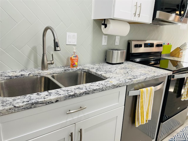 kitchen with sink, white cabinets, backsplash, stainless steel appliances, and light stone countertops