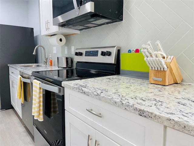 kitchen featuring stainless steel appliances, sink, white cabinets, and light stone counters