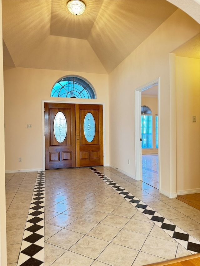 foyer entrance with high vaulted ceiling, light tile patterned floors, and a wealth of natural light