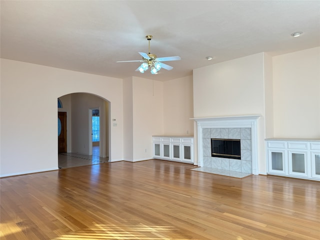 unfurnished living room featuring ceiling fan, a fireplace, and light wood-type flooring