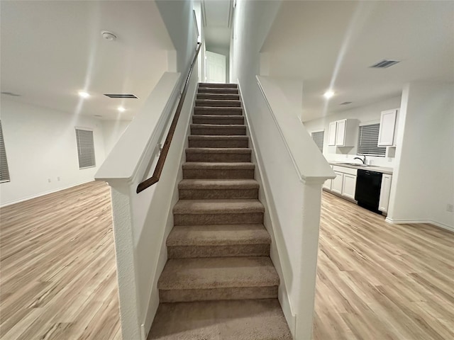 staircase featuring sink and hardwood / wood-style floors