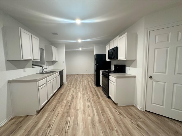 kitchen with light wood-type flooring, white cabinets, sink, and black appliances