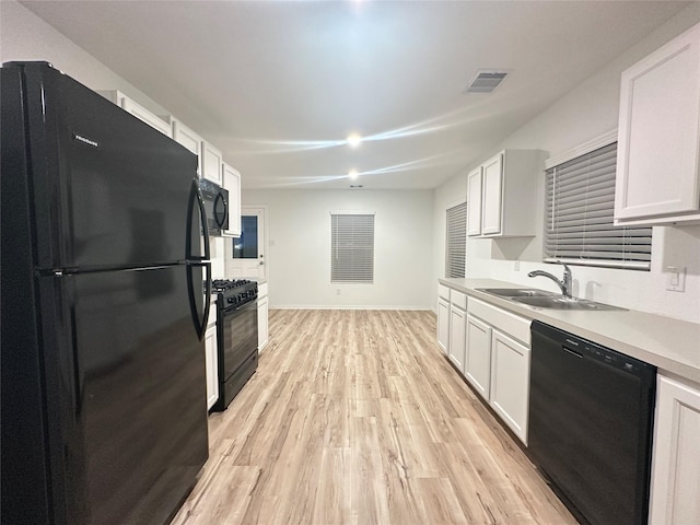 kitchen featuring white cabinetry, sink, light hardwood / wood-style flooring, and black appliances