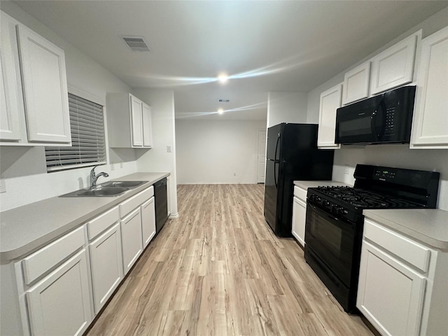 kitchen featuring sink, black appliances, and white cabinets