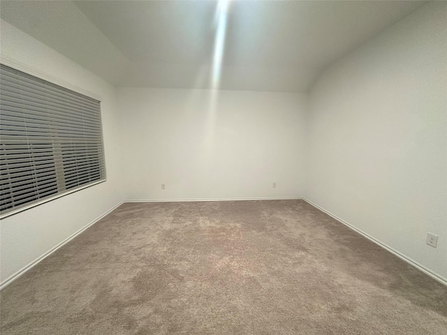 carpeted empty room with vaulted ceiling