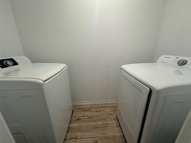 clothes washing area with independent washer and dryer and light hardwood / wood-style floors