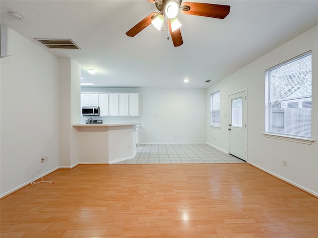 unfurnished living room featuring ceiling fan and light hardwood / wood-style flooring