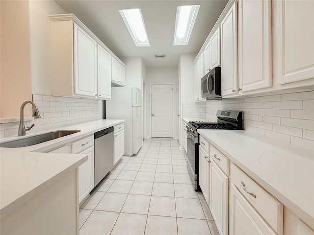 kitchen featuring sink, light tile patterned floors, stainless steel appliances, and white cabinets