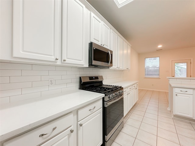 kitchen featuring stainless steel appliances, tasteful backsplash, light tile patterned floors, and white cabinets