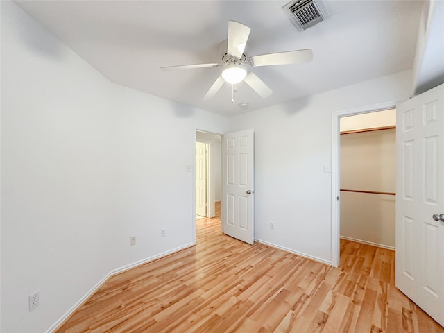 unfurnished bedroom with light hardwood / wood-style flooring, a walk in closet, a closet, and ceiling fan