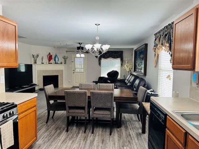 dining room with a tiled fireplace, wood-type flooring, sink, and a chandelier