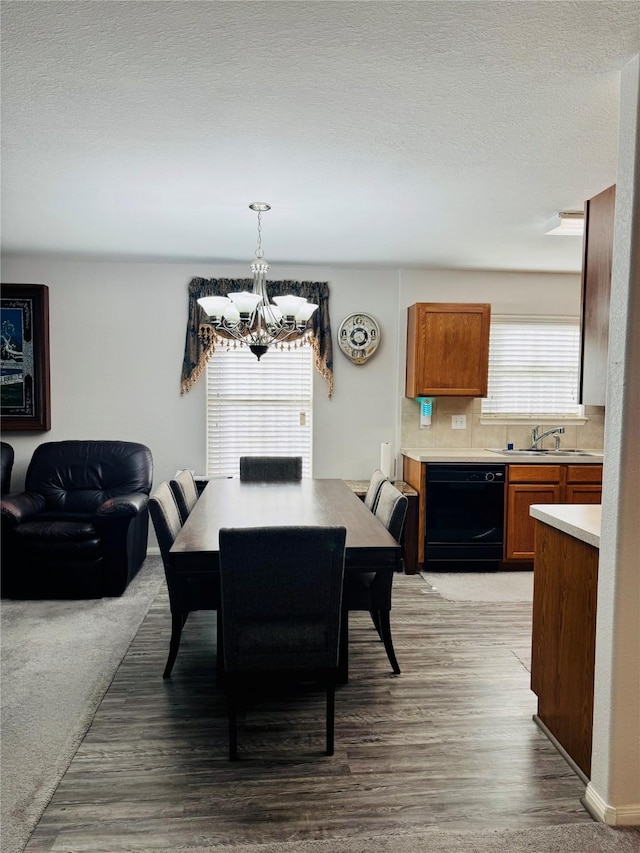 dining space featuring sink, a textured ceiling, light hardwood / wood-style floors, and a chandelier